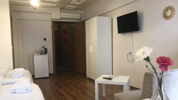 Una habitación de hotel con una cama, un escritorio, un televisor y un jarrón con flores.