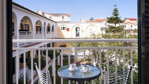 A balcony with a table, chairs, and a view of buildings. - Ragias Studios (Zakynthos)