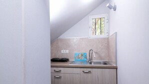 A small kitchen with a sink, a window, and a countertop. - Ragias Studios (Zakynthos)