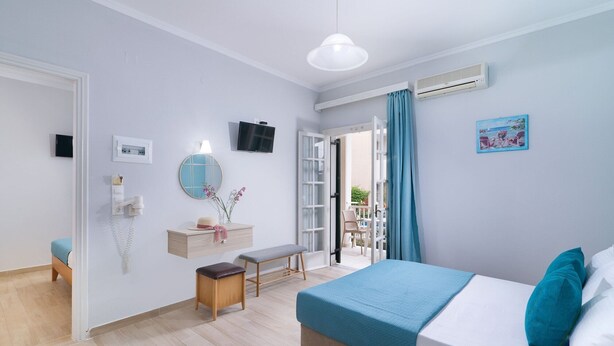 A bedroom with a bed, bedside table, mirror, and a view to an outdoor balcony. - Ragias Studios (Zakynthos)