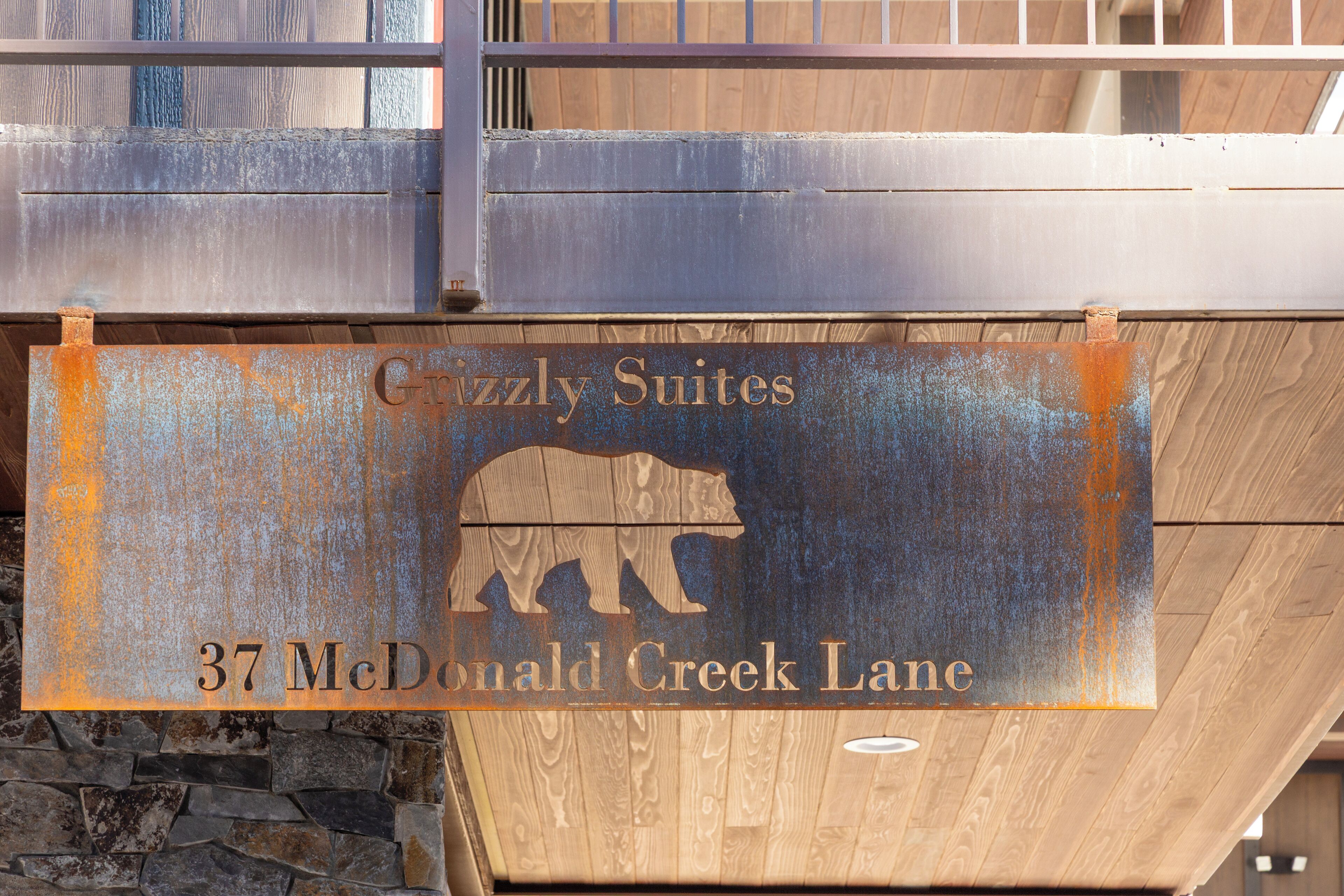 A sign for "Grizzly Suites" at 37 McDonald Creek Lane, featuring a bear logo.