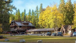 A rustic lodge with a cafe and mercantile, surrounded by autumn trees and parked cars. - New! Lake McDonald Townhome. In Glacier National Park! (West Glacier)