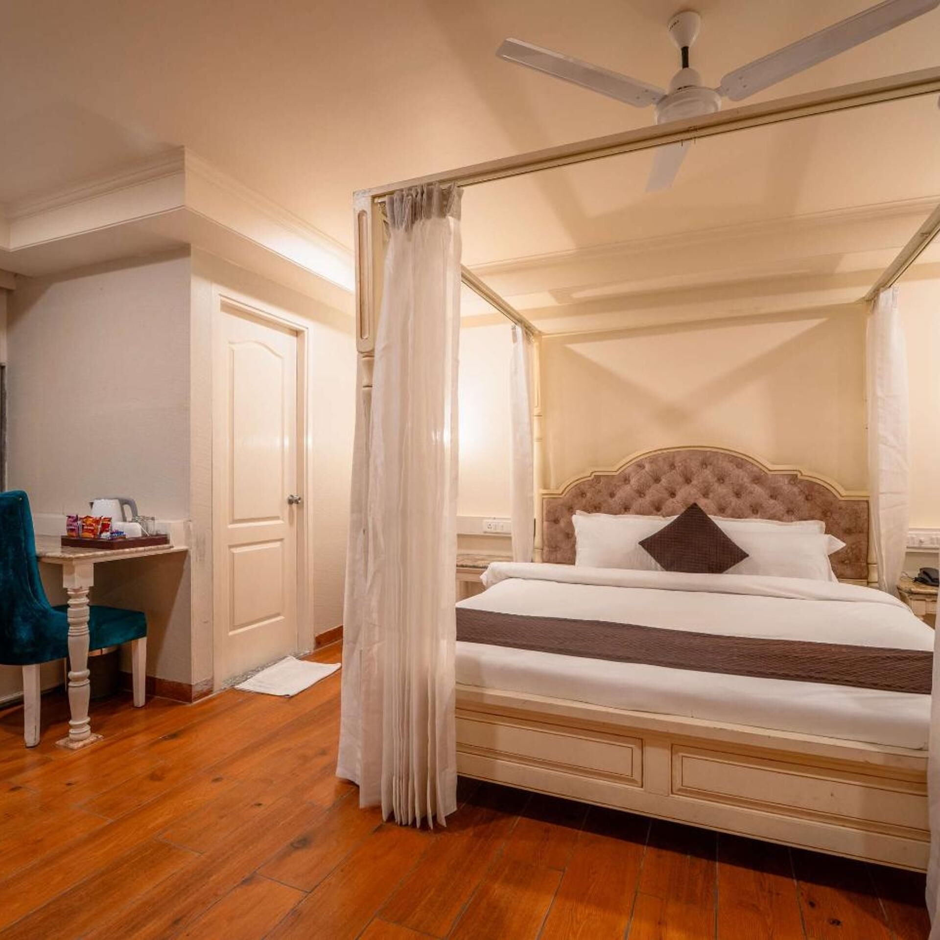 Una cama con dosel y mosquitera, un escritorio con silla y un ventilador de techo.