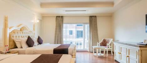 A hotel room with two beds, a ceiling fan, a large window with curtains, a white sofa, and a wooden cabinet.