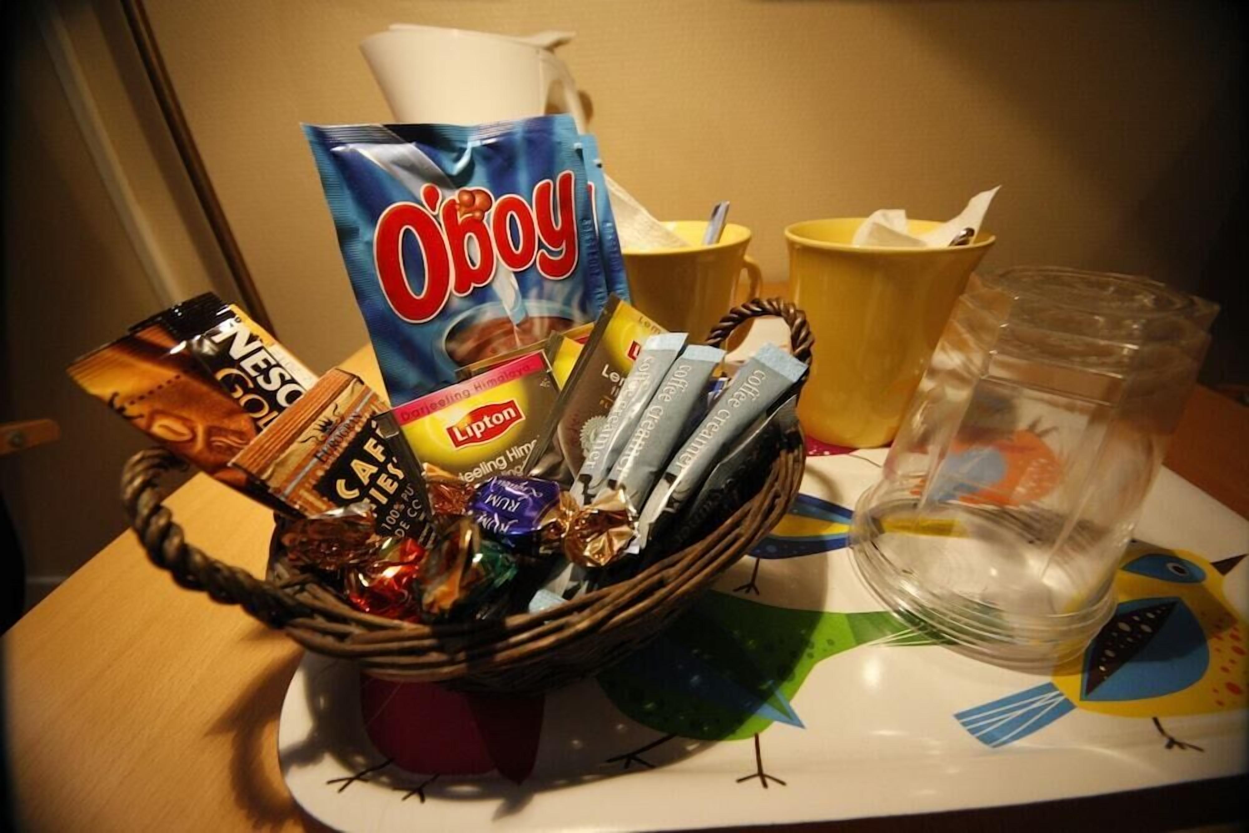 Un plateau avec un panier contenant un assortiment de collations, un sachet de thé Lipton, un sachet de café instantané Nescafé et un verre transparent avec une paille.