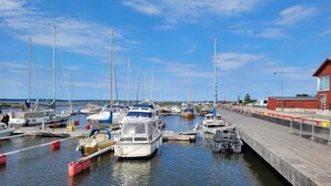 A marina with various boats docked, a wooden walkway, and a building on the right. - Mariestads Stadshotell (Mariestad)