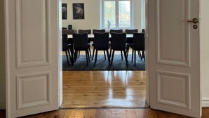 An open door leading to a dining area with wooden flooring, black chairs, and pendant lights. - Hotel Sirius (Kristianstad)