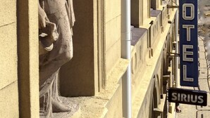 La façana d'un hotel amb una estàtua clàssica, un rètol que diu 'HOTEL' i un rètol que diu 'SIRIUS'.