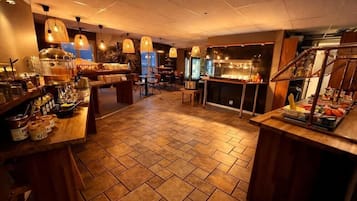 A restaurant with a tiled floor, wooden furniture, and hanging pendant lights.