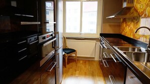 A compact kitchen with a window, wooden flooring, and stainless steel appliances. - Karlskrona Hostel (Karlskrona)