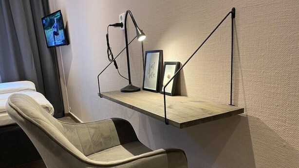 A modern hotel room with a bed, a desk with a lamp, and a TV mounted on the wall. - Karlskrona Hostel (Karlskrona)