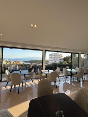 Ein moderner Essbereich mit großen Fenstern, Blick auf die Stadt und einem Tisch mit Stühlen.