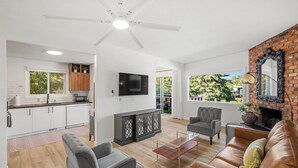 Un salón amplio con chimenea, televisor y una cocina moderna al fondo.