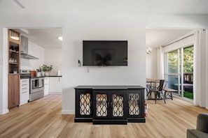 Une cuisine moderne avec des armoires blanches, un four encastré et un coin repas comprenant une table et des chaises.