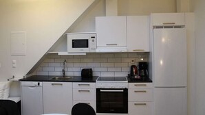 Eine kleine Küche mit weißen Schränken, einer Mikrowelle, einem Herd und einem Kühlschrank.