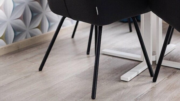 A modern dining area with a geometric patterned wall, a wooden table, and black chairs. - Hotel Oddsson (Reykjavik)
