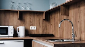 A compact kitchen with a microwave, kettle, and wooden cabinetry. - Hotel Oddsson (Reykjavik)