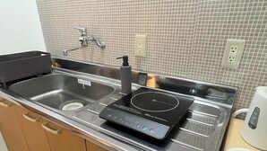 A kitchen with a stainless steel sink, a black induction cooktop, and a coffee maker. - Assi (Yufu)