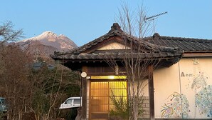 A traditional Japanese building with a tiled roof, a wooden entrance, and a mural on the wall. - Assi (Yufu)