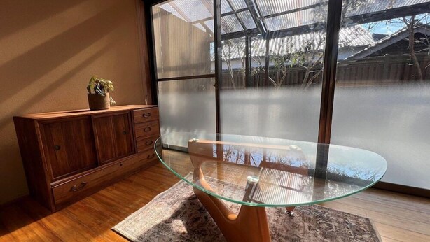 A modern room with a glass-top table, wooden cabinet, and large windows. - Assi (Yufu)
