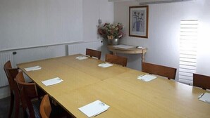 A conference room with a long table, six chairs, and papers on the table.