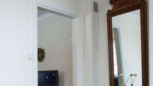 A hotel room with a bed, a dresser, a mirror, and a television in the background.