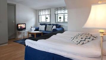 A bedroom with a bed, a desk, a chair, a lamp, and a television.
