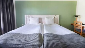 A double bed with a headboard, a desk with a chair, and a lamp. - Hotel Mullsjö (Mullsjö)
