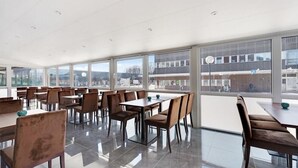 A spacious dining area with large windows, modern furniture, and a clean, reflective floor. - First Hotel Oxelösund (Oxelosund)