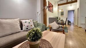 Una sala de estar con un sofá, una mesa de centro y una silla. Hay una planta sobre la mesa de centro.