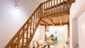 Una escalera que lleva a un nivel superior, una sala de estar con un sofá, una mesa de centro y un comedor con sillas y una mesa.