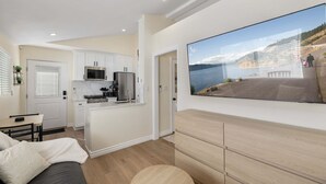 A modern kitchen with white cabinets, stainless steel appliances, and a large window overlooking a scenic waterfront. - Luxury 1BR Suite Kitchen, Fireplace, Laundry, BBQ (Simi Valley)