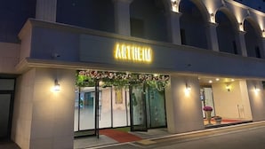 Un hôtel reconnaissable à son grand panneau « ARTHEIM », à ses larges fenêtres en arc de cercle et à son entrée surmontée d’un tapis rouge.