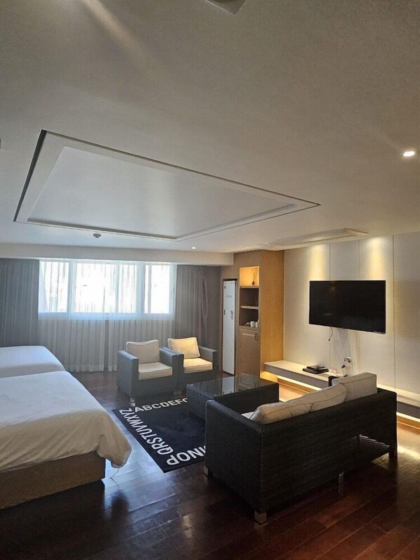 Een moderne hotelkamer met een groot bed, een bank, een televisie en een bureau.