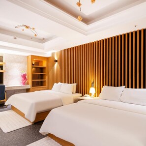 A hotel room with two beds, a wooden slat wall, a desk with a lamp, and a small seating area with a chair. - Bentley Hotel Chungjang (Gwangju)