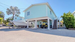 Ein zweistöckiges Haus mit überdachter Garage und einem Boot, das vor der Tür liegt.