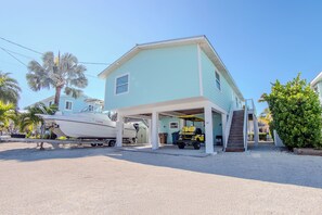 Ein zweistöckiges Haus mit überdachter Garage und einem Boot, das vor der Tür liegt.