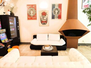 A living room with a white sofa, a coffee table, and a wall-mounted TV. There are three framed artworks above the sofa. - Brit Hotel Suisse ET Bordeaux (Grenoble)