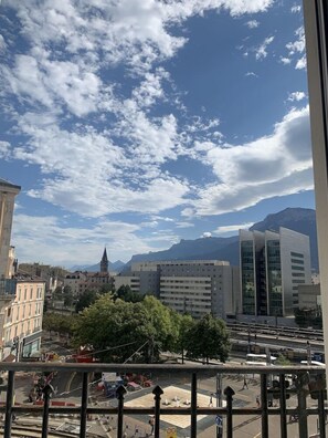 A cityscape with modern buildings, a church spire, and mountains in the background. - Brit Hotel Suisse Et Bordeaux (Grenoble)
