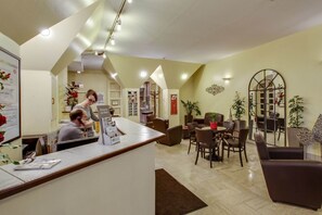 A hotel lobby with a reception desk, seating area, and a staircase leading to another floor.