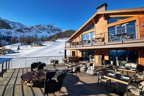A wooden lodge with a deck overlooking a snowy mountain landscape. - Le Massif Hotel & Lodge Courmayeur (Courmayeur)