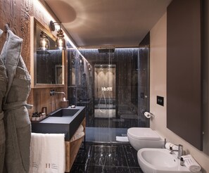 A modern bathroom with a wooden vanity, a glass-enclosed shower, a white sink, and a toilet. - Le Massif Hotel & Lodge Courmayeur (Courmayeur)