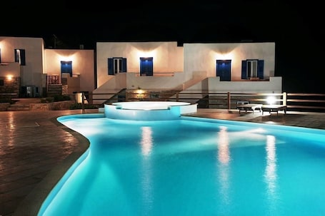 A modern villa with a swimming pool, outdoor seating, and a staircase leading to the upper level.