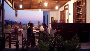 A group of people seated around a table in an outdoor setting with a pool in the background. - Amorgion Hotel (Amorgos)