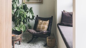 A cozy corner with a chair, a large plant, and a framed artwork on the wall. - Yust Antwerpen (Antwerp)