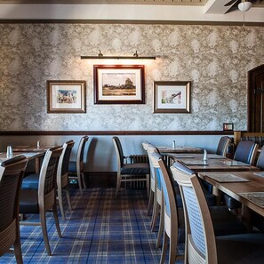 Un restaurante con una pared de mármol, cuadros enmarcados y una alfombra de cuadros.