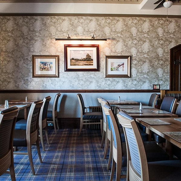 A restaurant with a marble wall, framed pictures, and a plaid carpet.