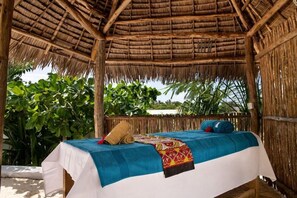 A thatched-roof outdoor bedroom with a bed, pillows, and a blanket. - Nyumbani Residence (Jambiani)