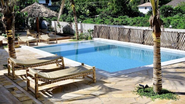 Una piscina amb gandules i un para-sol de palla.
