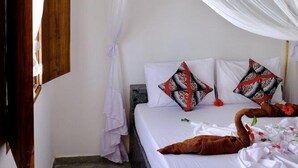 Un dormitori amb un llit, cortines blanques i un cigne decoratiu al llit.